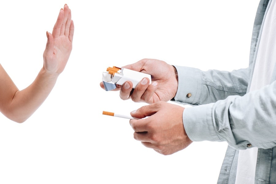 Homme regardant son paquet de cigarette et prenant conscience de la nécessité d’arrêter de fumer.